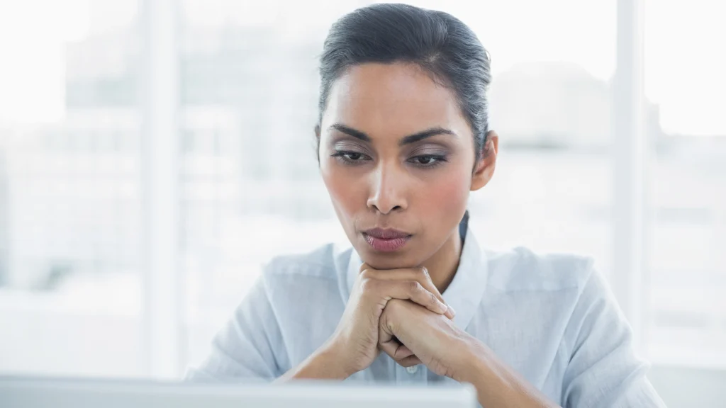 Woman focused, looking at her computer and thinking.